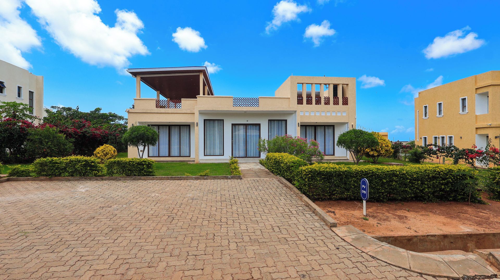 Una casa moderna de dos pisos con entrada pavimentada y un jardín bien cuidado.