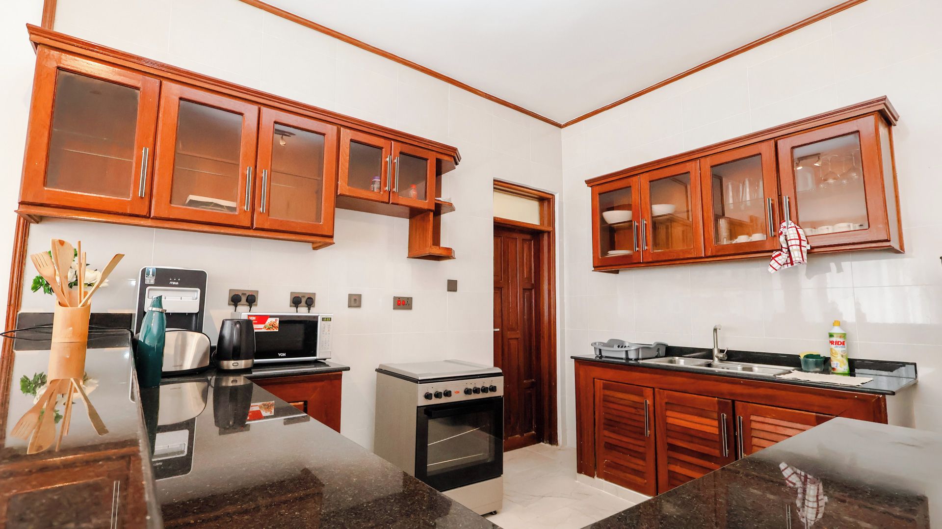 Una cocina compacta con armarios de madera, microondas, estufa y pileta.