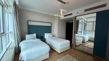 Habitación de hotel con dos camas, un espejo grande y vistas a la ciudad desde la ventana.