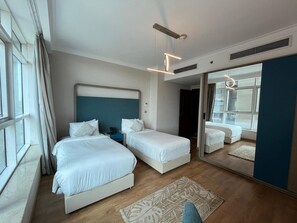 Habitación de hotel con dos camas, un espejo grande y vistas a la ciudad desde la ventana.