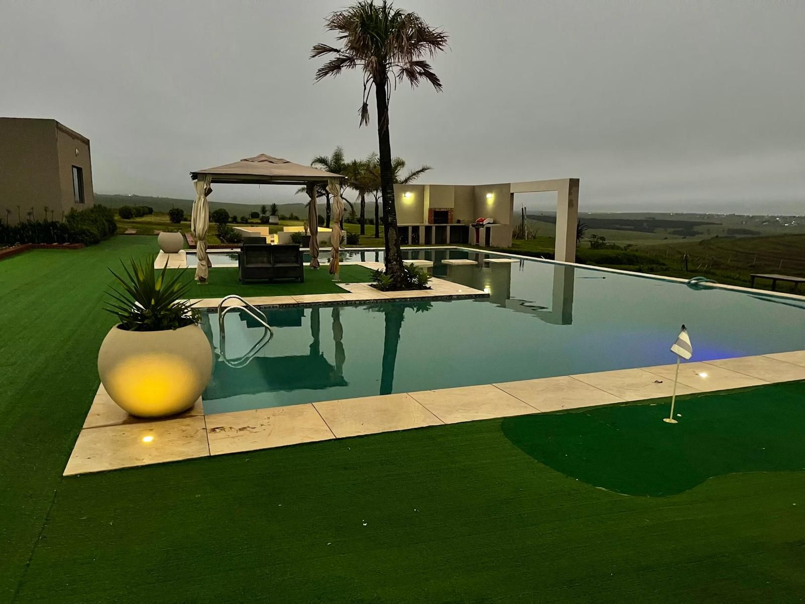 Una piscina con una palmera, un pabellón y vistas al paisaje.