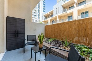 A balcony with a black gate, two chairs, a small table, and a plant. - New York industrial style JVC (Dubai)