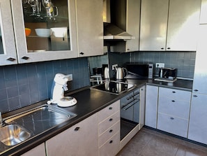 A modern kitchen with stainless steel appliances, a built-in oven, and a coffee maker. - 100-square-meter house with a garden and balcony, 4 rooms, 2 bathrooms (Kamen)