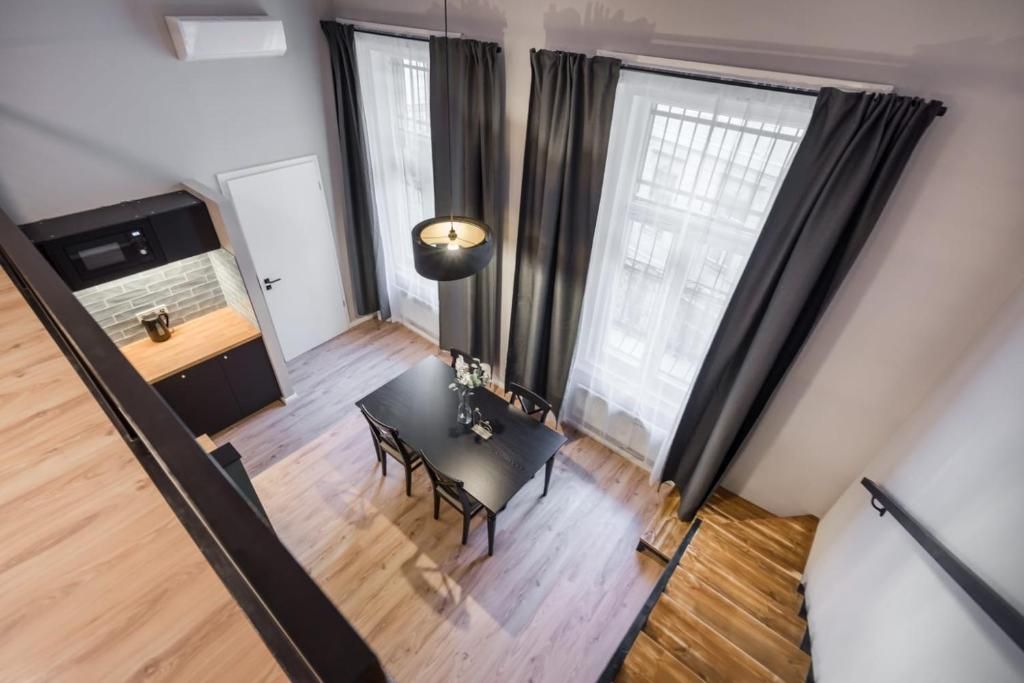 A modern kitchen with a built-in oven, a dining area with a table and chairs, and a large window with curtains.