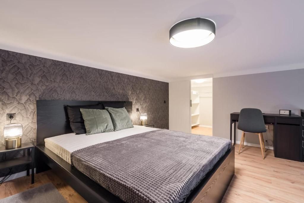 A bedroom with a bed, bedside tables, a desk, and a chair.