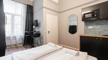 A hotel room with a bed, a desk with chairs, a television, a microwave, and a tiled backsplash.