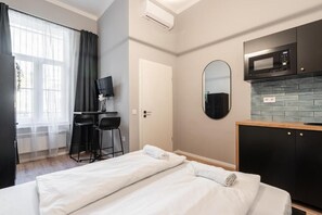 Habitació d'hotel amb llit, escriptori amb cadires, televisió, microones i resclosa de rajola.