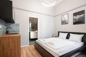 A modern bedroom with a wooden bedside table, a bed with white linens, a black headboard, and two framed pictures on the wall. - R38 - Boutique Apartments by BQA (Budapest)