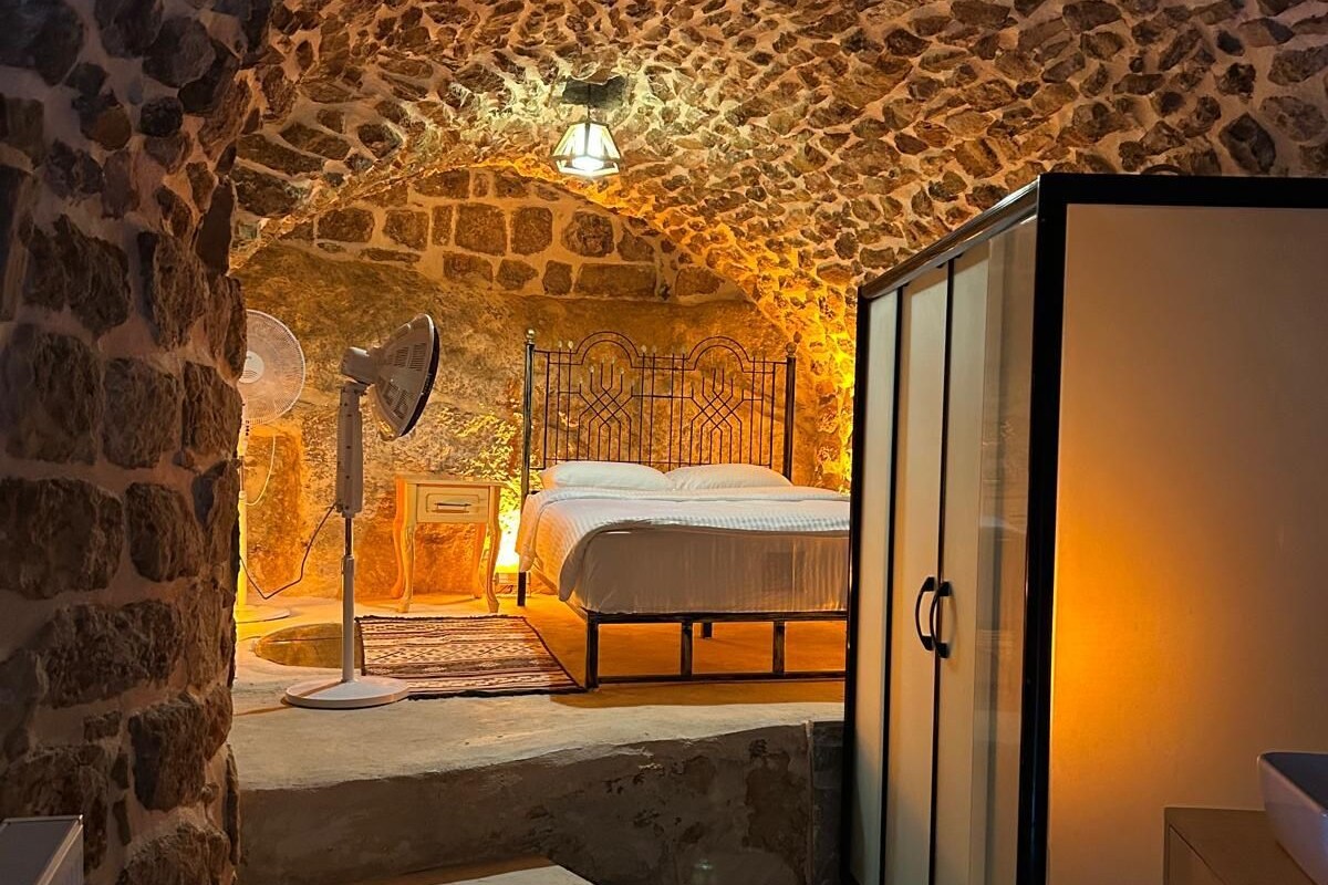 A bedroom with a stone ceiling, a bed, a wardrobe, and a radiator.