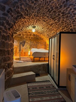 A bedroom with a stone ceiling, a bed, a wardrobe, and a radiator. - ASEL KONAK (Mardin)