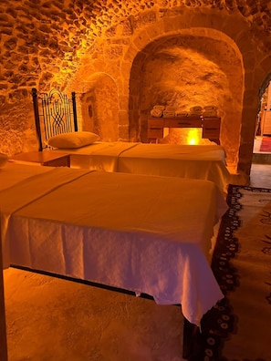 Una habitación con dos camas, una pared de piedra y un aparador de madera.