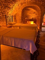 A room with two beds, a stone wall, and a wooden chest of drawers.