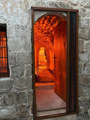 Un arco de piedra que da paso a una habitación con una puerta de madera y un ventanal pequeño.