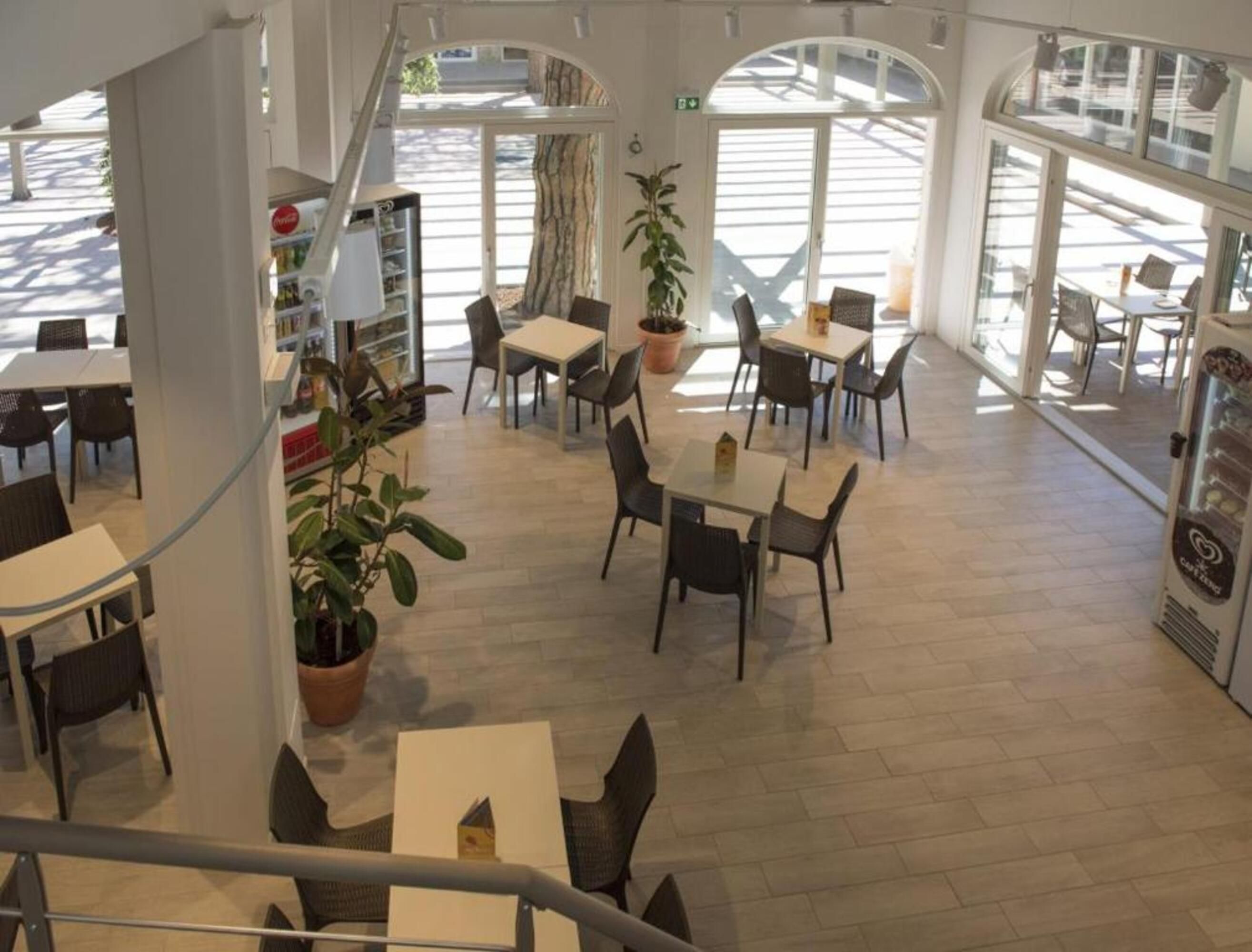 A spacious indoor area with multiple tables and chairs, a staircase, and a vending machine.