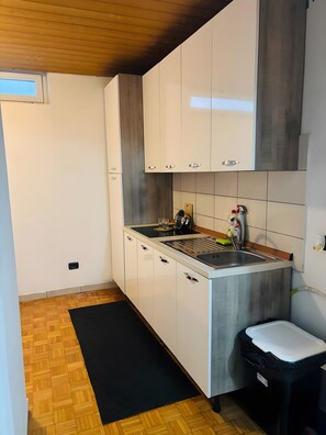 Eine moderne Küche mit weißen Schränken, einer Edelstahl-Spüle und einer schwarzen Mülltonne.