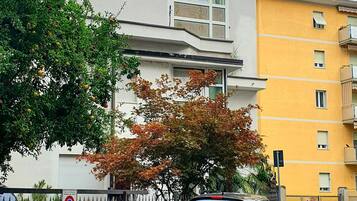 A parking area with a black car, a building with a white facade, and a yellow building in the background.