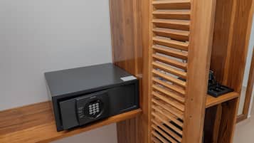 A black security keypad on a wooden shelf, a wooden slatted partition, and a black object on a lower shelf.