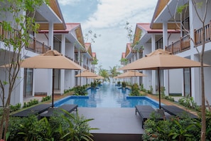 Un hotel con piscina central, varios balcones y zonas de estar al aire libre.