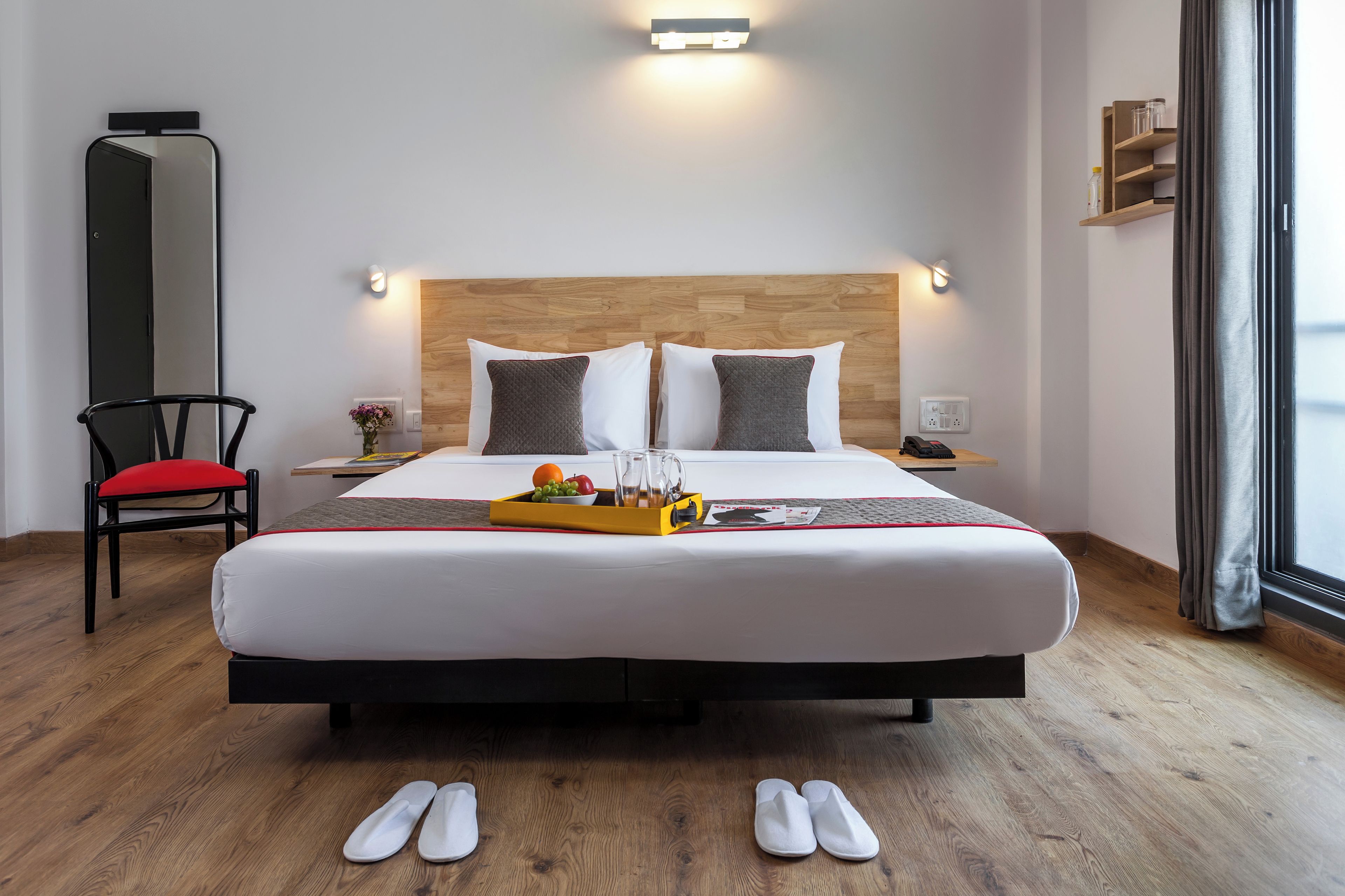 Hotellihuone, jossa on sänky, yöpöytä, tuoli ja näkymä ulos.