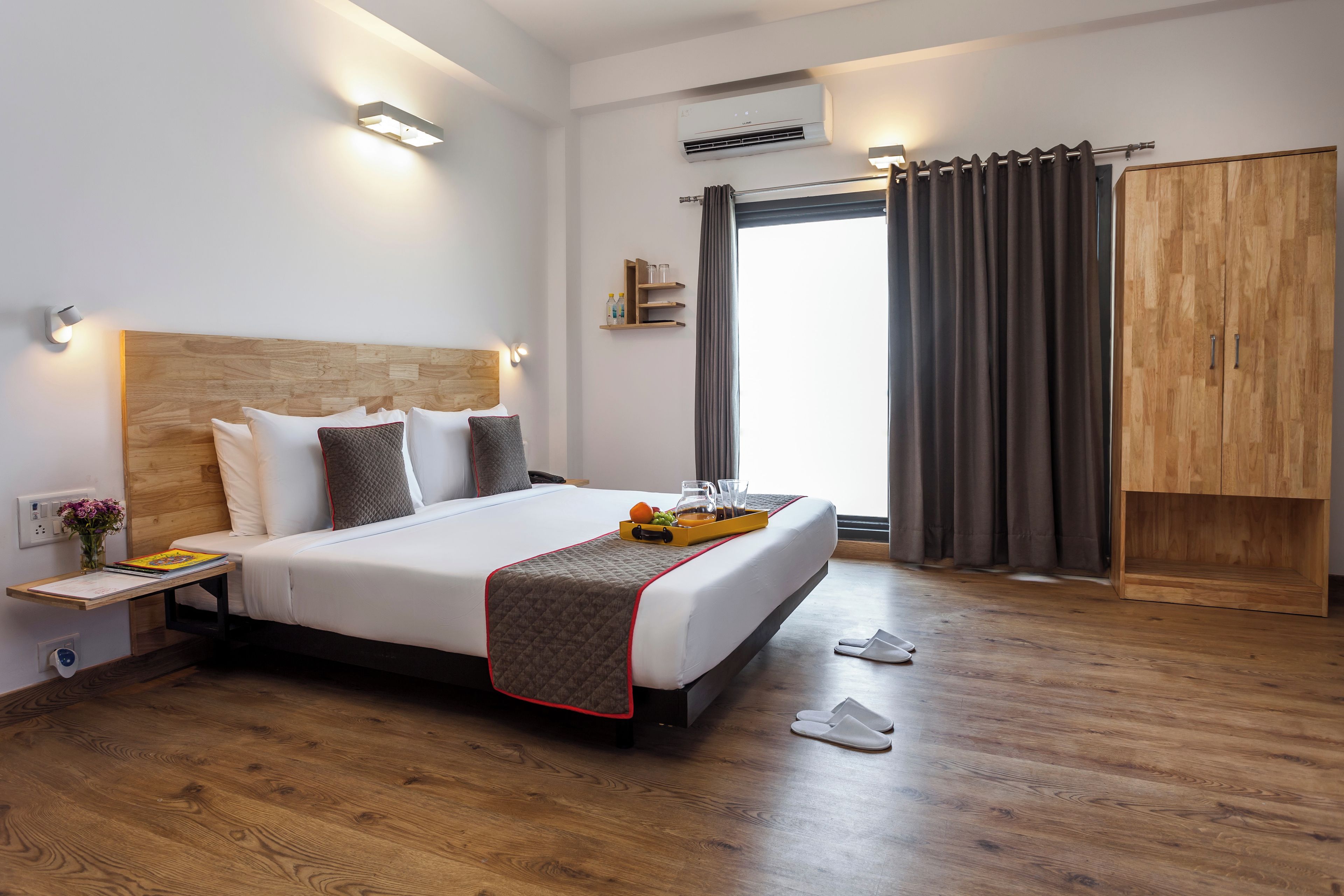 A hotel room with a large bed, bedside tables, a wardrobe, and a window with curtains.