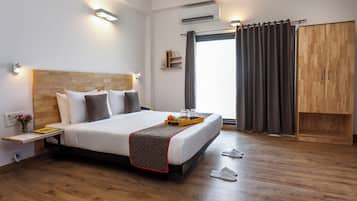 A hotel room with a large bed, bedside tables, a wardrobe, and a window with curtains.
