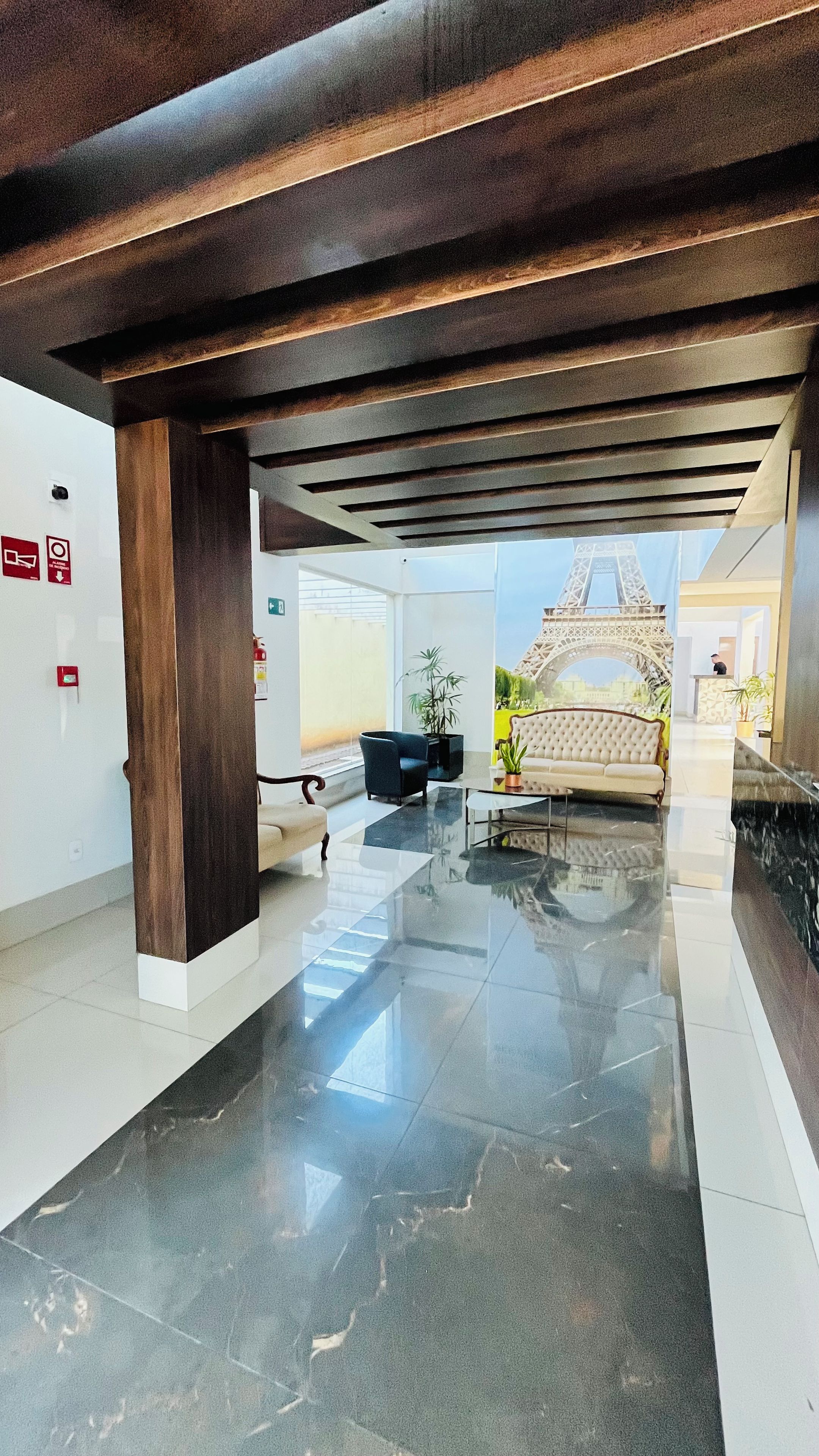 Et hotellobby med et moderne design, inklusive en receptionsdisk, et loungeområde og udsigt til Eiffeltårnet.