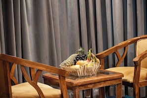 A room with two wooden chairs, a small table, and a fruit basket on the table. - Hayat Residency pahalgam (Pahalgam)