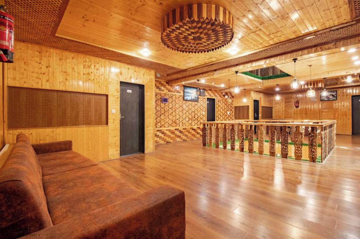 A wooden interior with a sofa, a patterned wall, and a railing.