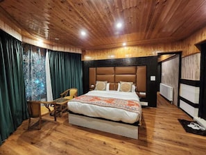 A wooden-paneled bedroom with a bed, a chair, and a table. - Hayat Residency pahalgam (Pahalgam)