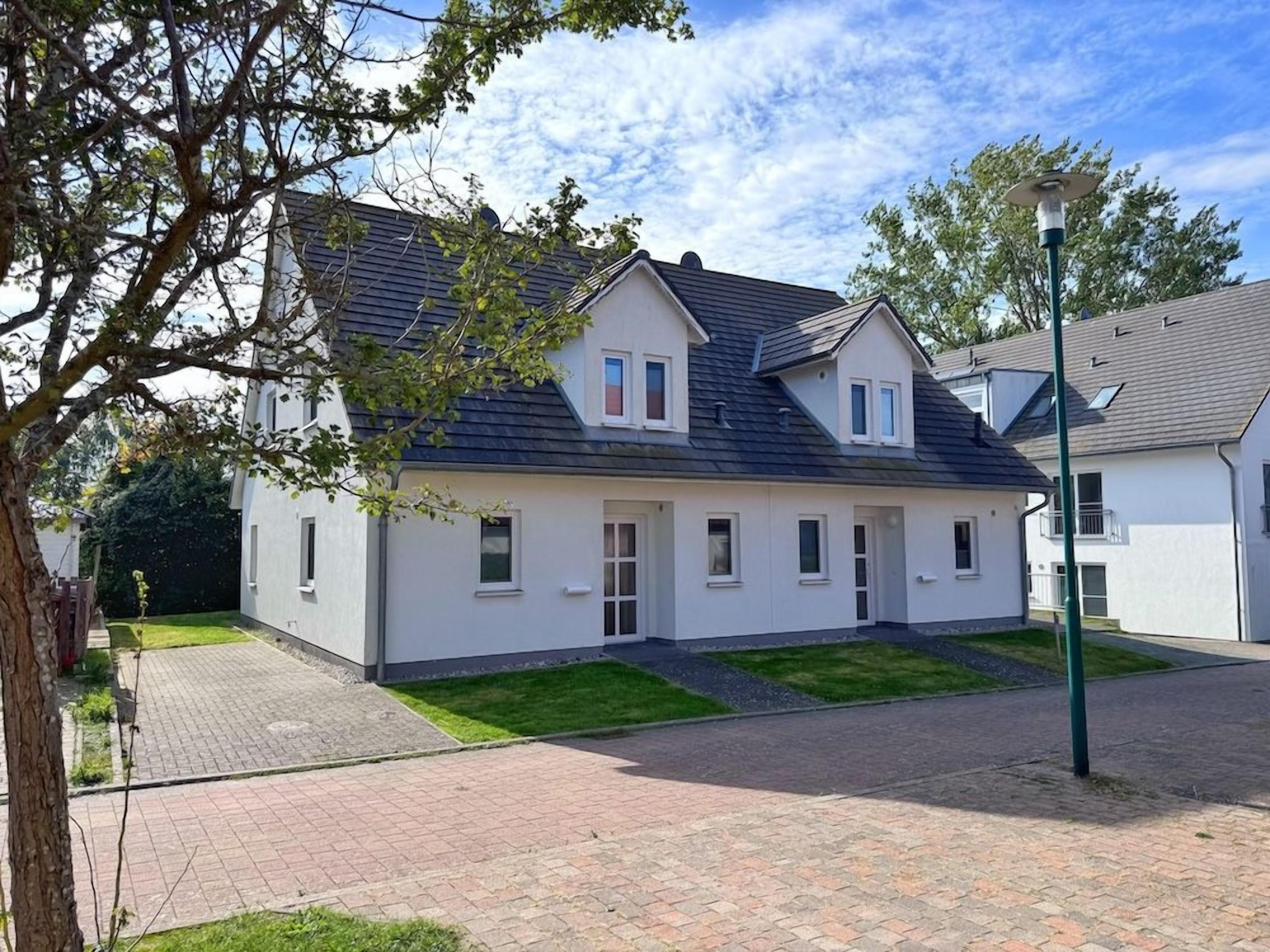 A two-story residential building with a flat roof, a paved driveway, and a well-maintained lawn.