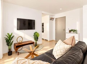 A modern living room with a leather sofa, a glass coffee table, and a flat-screen TV mounted on the wall. - Boutique Penthouse in the Historic centre! (Lagos)