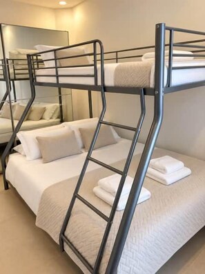 Uma cama beliche com escada, um sofá e um espelho num quarto.