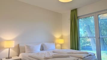 Una habitación de hotel con una cama, dos lámparas de noche, una mesita de noche y una ventana con cortinas.