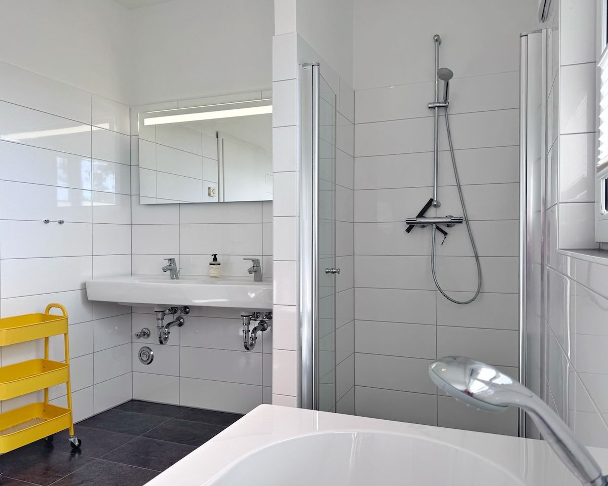 A modern bathroom with a white sink, mirror, and shower.