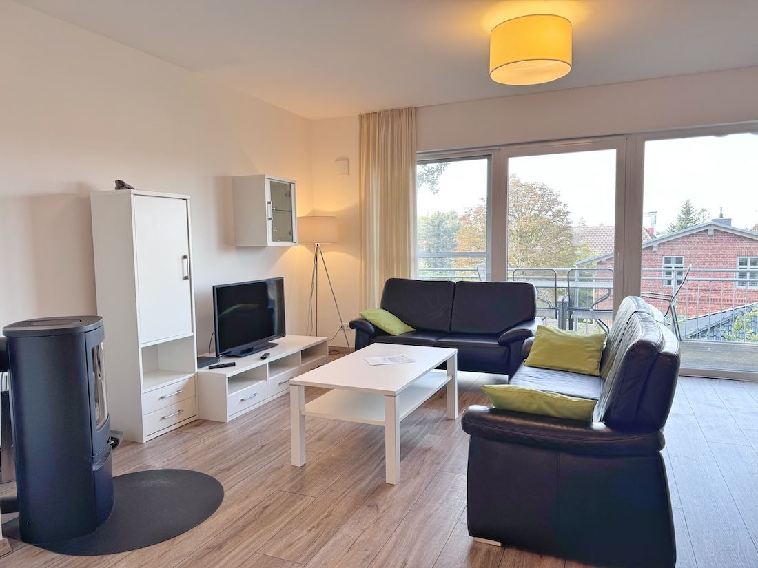 En moderne stue med en sofa, sofabord, fjernsyn og skab.