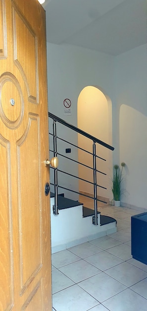 A wooden door with a round handle, a metal staircase with a handrail, and a wall-mounted sign with a no-smoking symbol. - Apartment '3. Grande A Bolzano' with Mountain View and Wi-Fi (Bolzano)