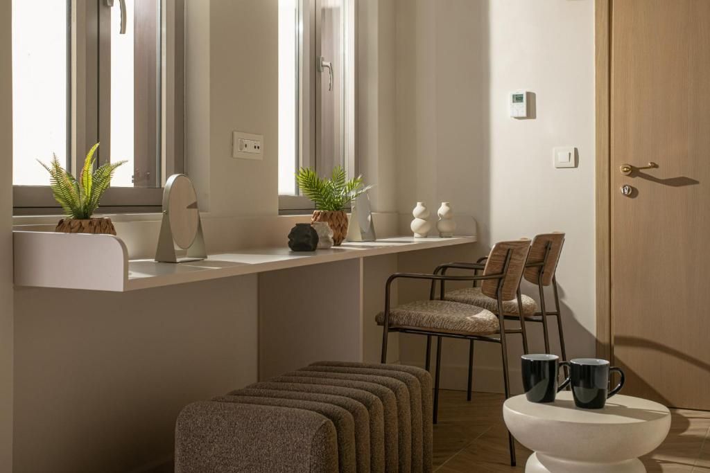 Une salle de bain moderne avec un meuble-lavabo blanc, deux plantes en pot, un miroir et des toilettes sur un socle blanc.