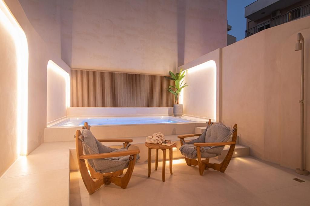 Un espace bien-être comprenant un jacuzzi, des chaises en bois et une petite table.