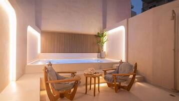 Un espace bien-être comprenant un jacuzzi, des chaises en bois et une petite table.