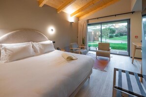 A modern hotel room with a large bed, a desk, and a view of the outdoors. - Paraiso Villas & SPA (Guimaraes)