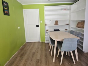 A room with a wooden floor, a white door, a table with chairs, and a white shelving unit with baskets. - Hokio Hideaway | Private 2-Bedroom Rural Guest Wing | Sleeps up to 6 (Hokio Beach)