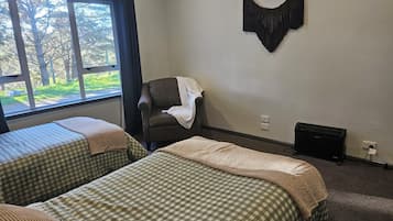 A room with two beds, a chair, a wall-mounted decoration, and a radiator.