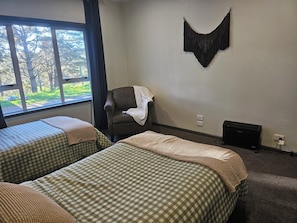 A room with two beds, a chair, a wall-mounted decoration, and a radiator.