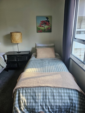 Een slaapkamer met een bed, een lamp, een schilderij en een raam.