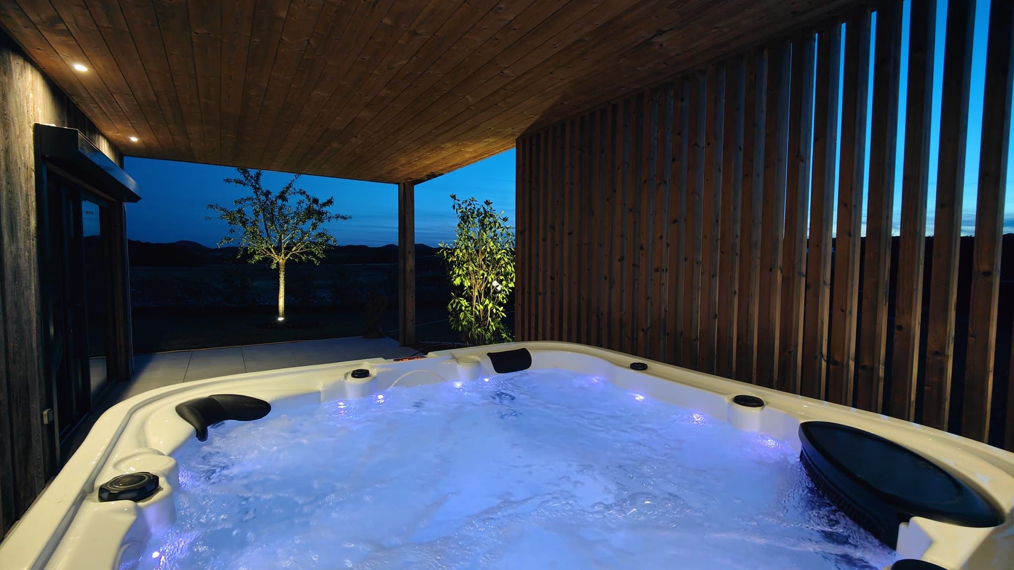 Een hottub met een houten plafond en wanden, omgeven door een houten hek.