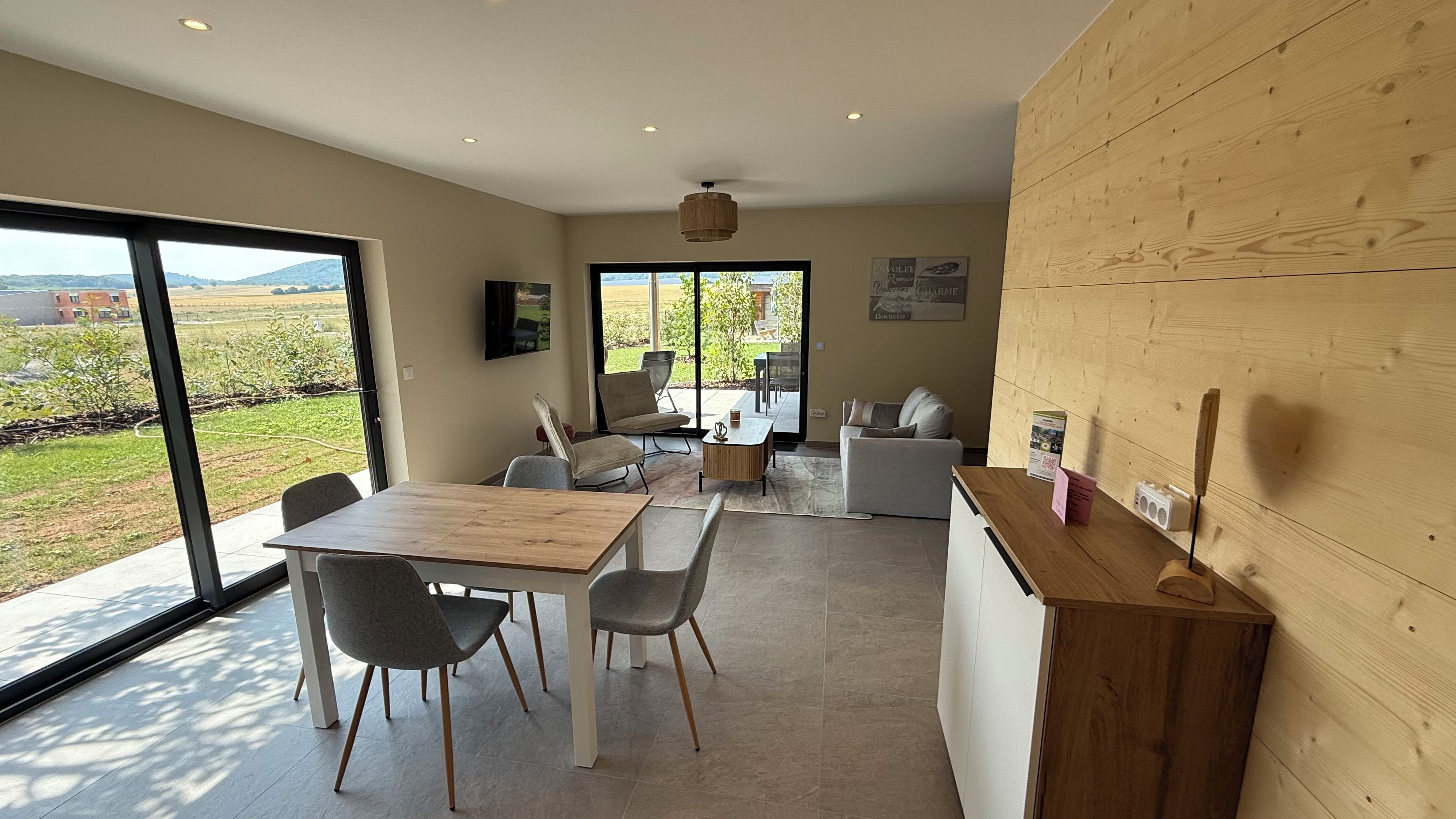 A modern kitchen with a wooden countertop, a dining area with chairs, and a view of the outdoors.