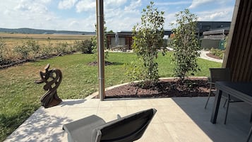 Een terras met tuinmeubilair, een beeld en uitzicht op een gebouw en het landschap.