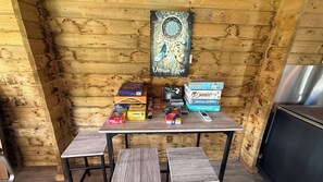 A wooden interior with a table displaying various board games and a dreamcatcher. - Osmose Spa Lodge (Ingwiller)