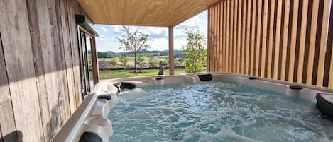 A hot tub with a wooden exterior and a view of a landscape.