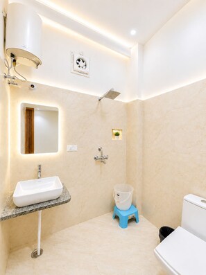 Ein modernes Badezimmer mit einem weißen Waschbecken, einer Duschbrause, einer Toilette und einem kleinen Hocker.